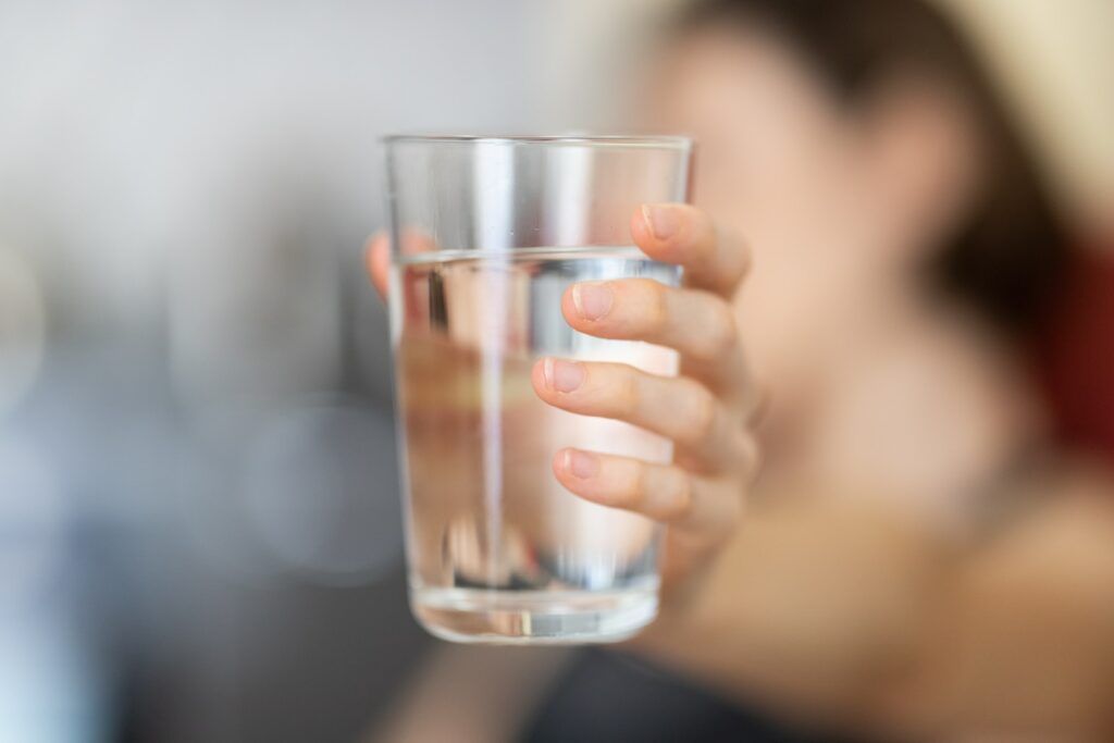 Persoon houdt een glas water vast voor gezondheidsredenen. 