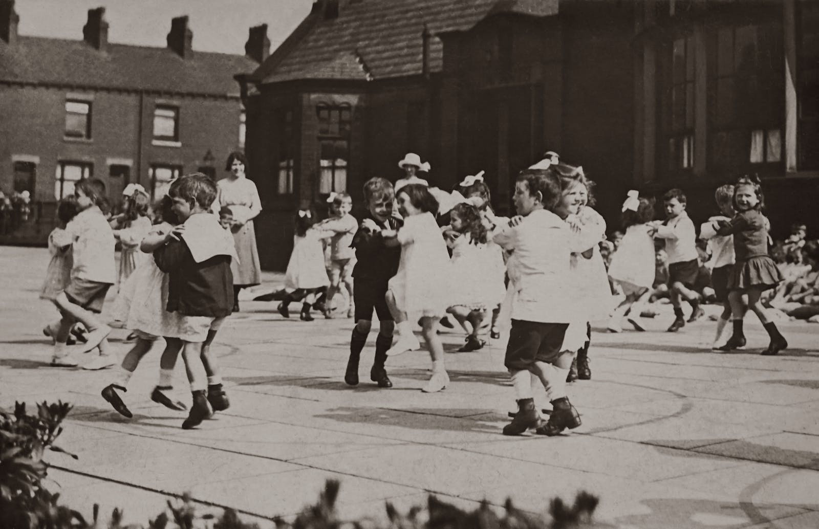 Grayscale Photo of Children Dancing on School Ground