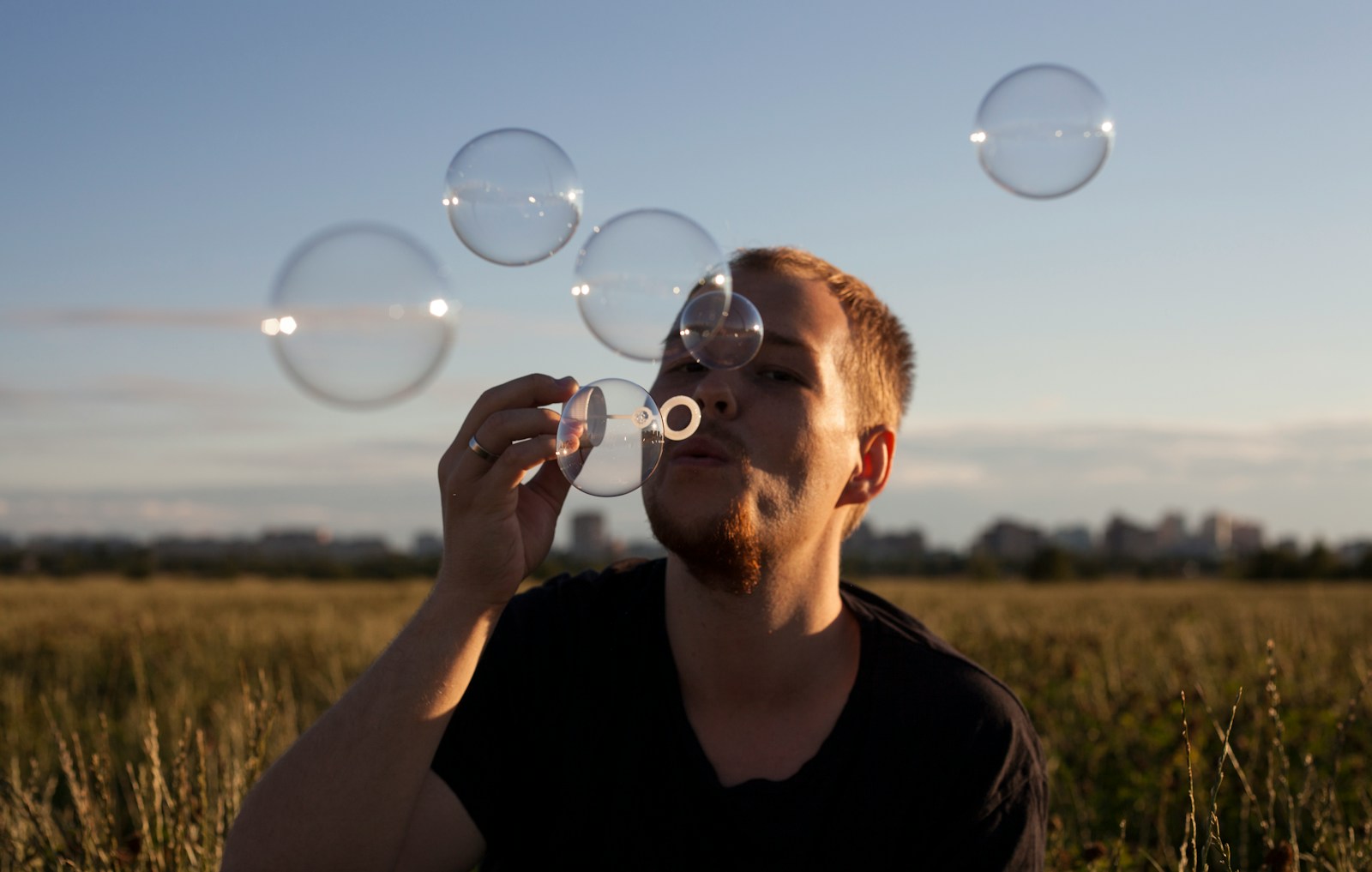 man in black crew neck shirt blowing bubbles