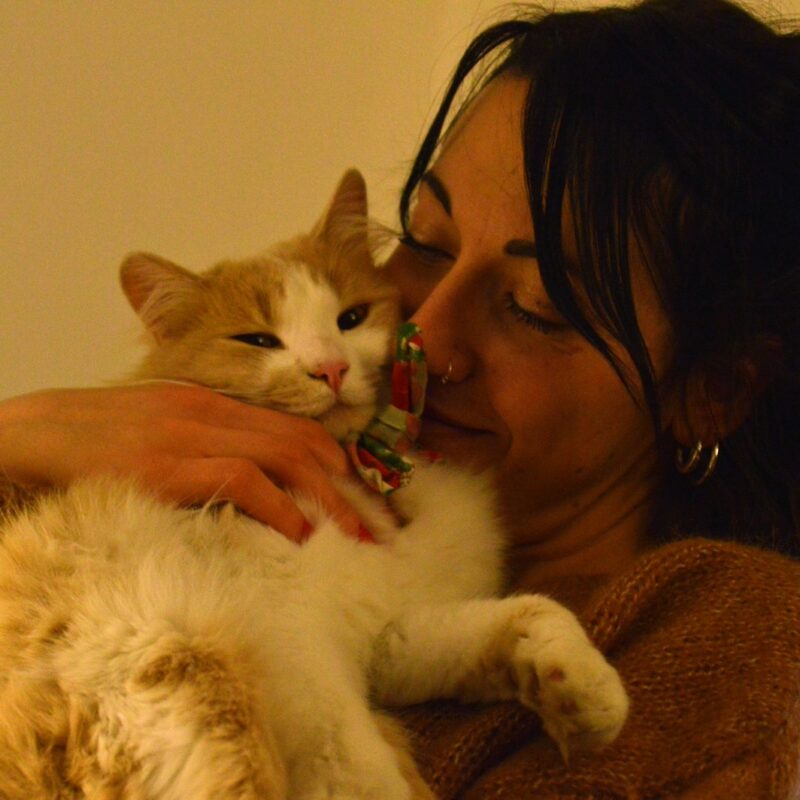 woman in black tank top holding white cat