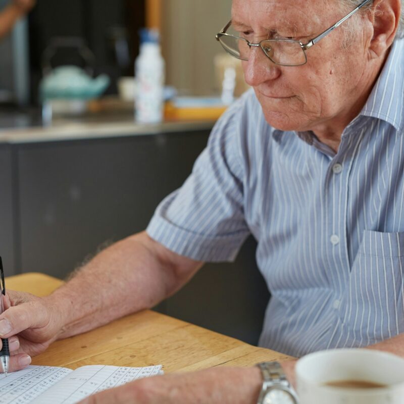 a man sitting at a table writing on a piece of paper