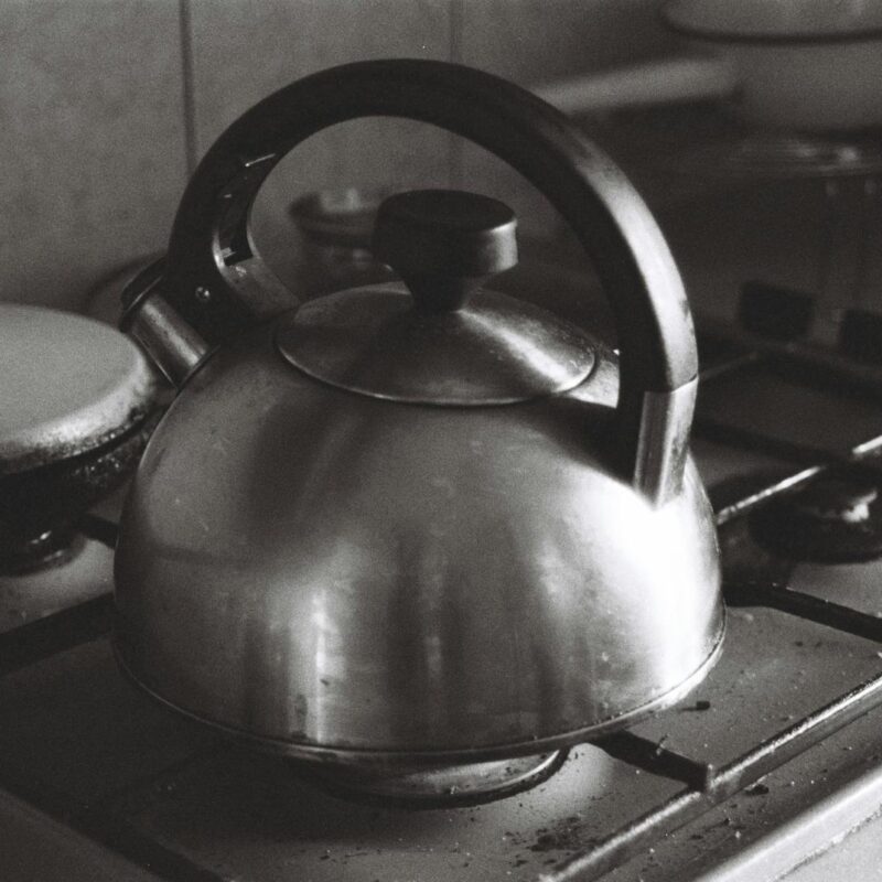 A monochrome image of a vintage kettle on a kitchen stove, classic and timeless.