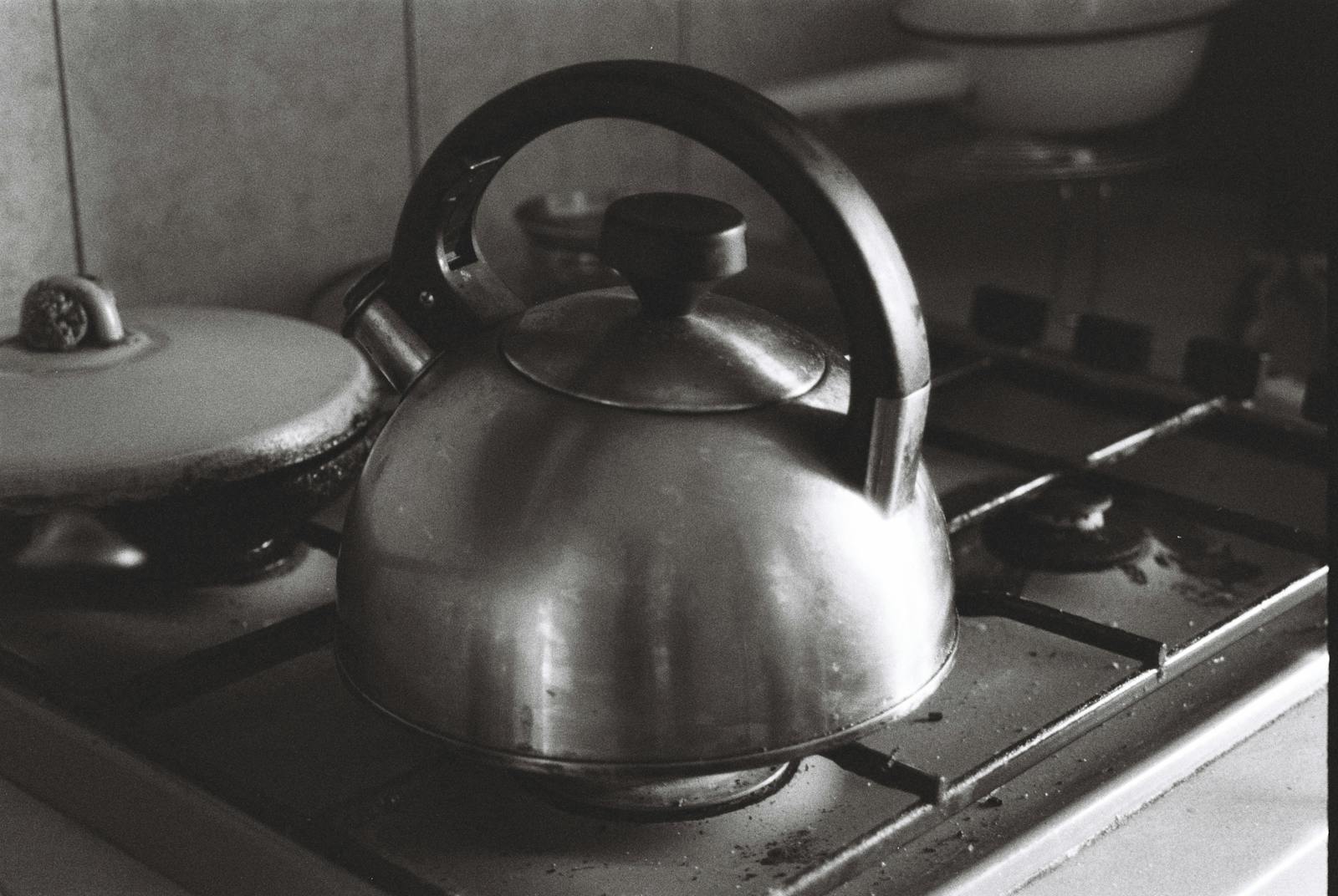 A monochrome image of a vintage kettle on a kitchen stove, classic and timeless.